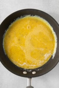 A frying pan with a yellow liquid in it.