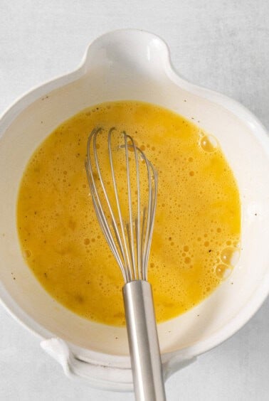 A white bowl with a whisk in it.