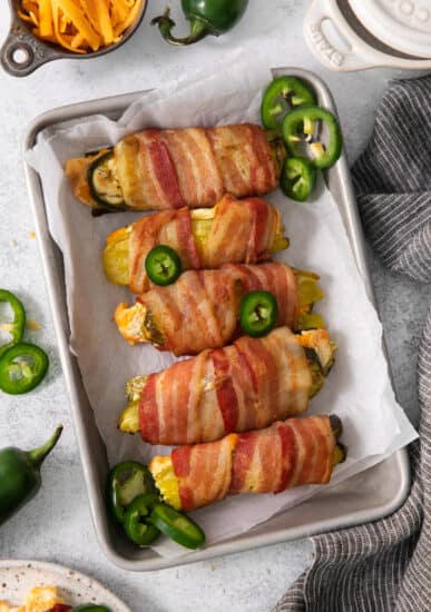 Bacon wrapped peppers on a baking sheet.