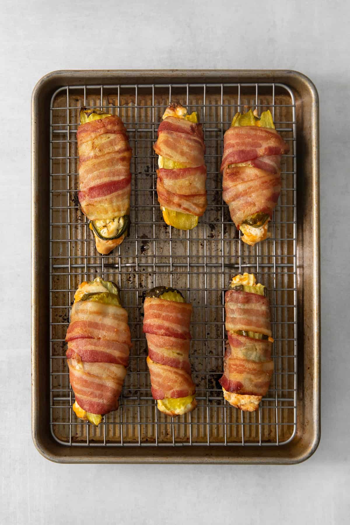 Bacon wrapped peppers on a baking sheet.