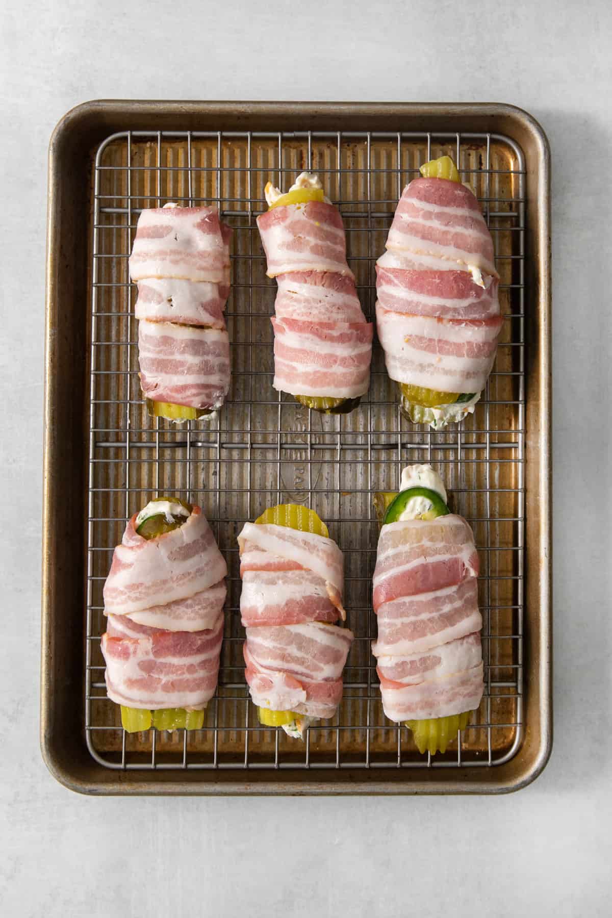 Bacon wrapped peppers on a baking sheet.