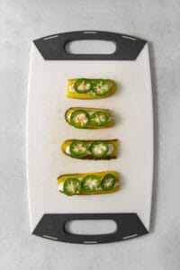 Four stuffed peppers on a cutting board.