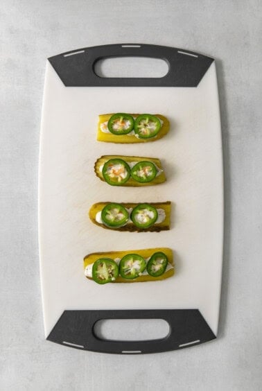 Four stuffed peppers on a cutting board.