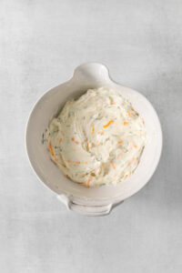 A white bowl filled with a mixture of carrots and cream cheese.