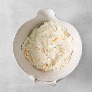 A white bowl filled with a mixture of carrots and cream cheese.