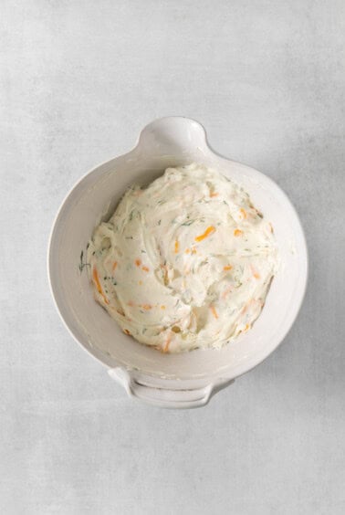 A white bowl filled with a mixture of carrots and cream cheese.