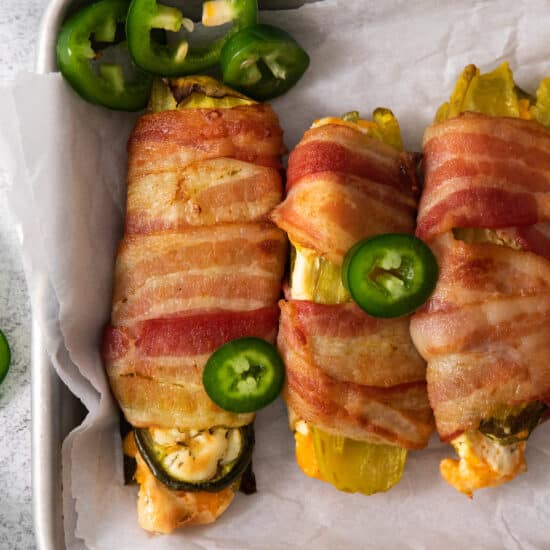 Bacon wrapped jalapeno peppers on a baking sheet.