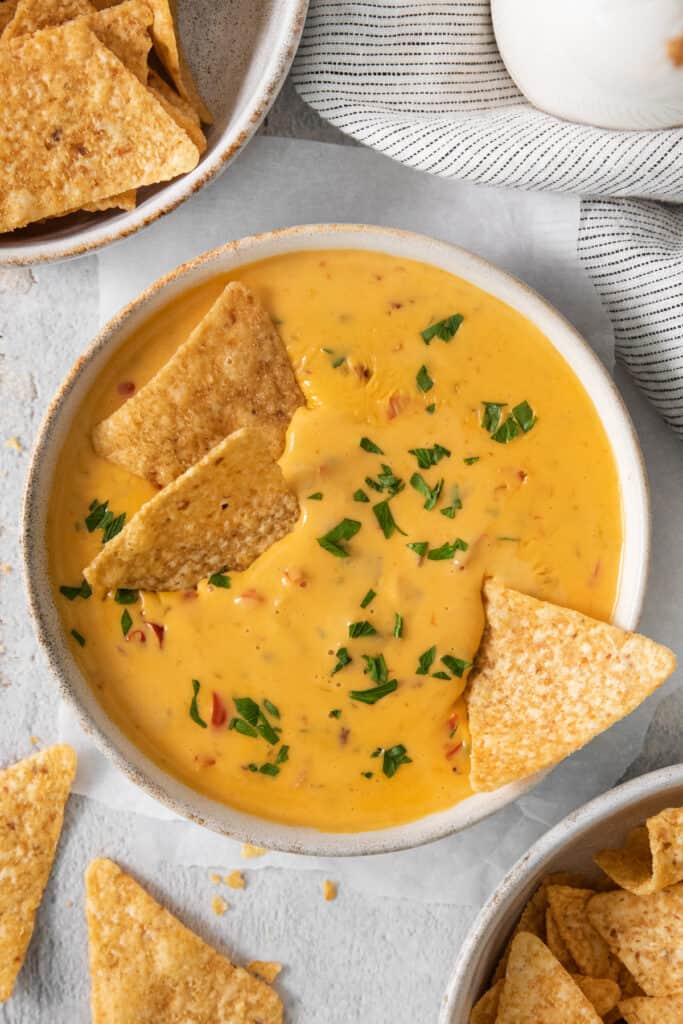 A bowl of cheesy dip with tortilla chips.