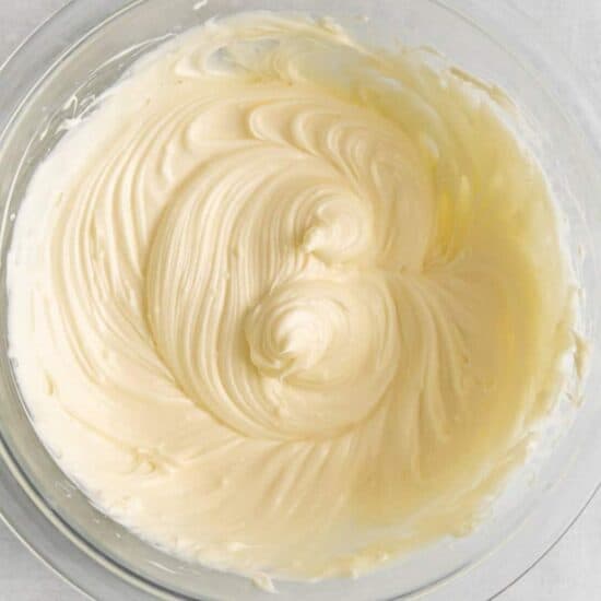 Whipped cream in a bowl on a white surface.