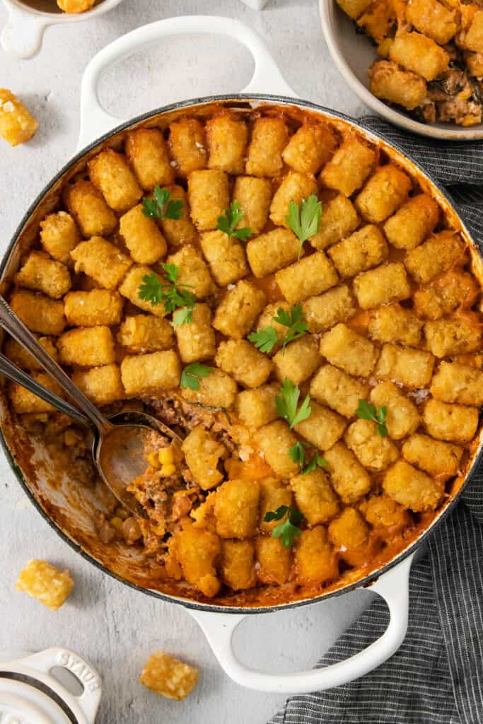 A cowboy casserole dish of tater tots in a pan with a spoon.