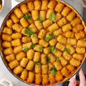 A cowboy holding a pan of tater tots.