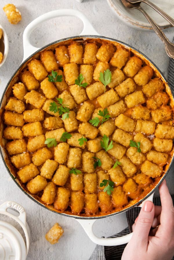 A cowboy holding a pan of tater tots.