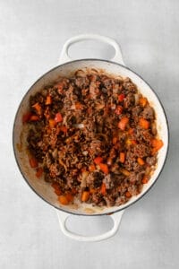 A cowboy casserole with meat and vegetables in a white pan.