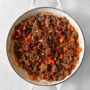 A cowboy casserole with meat and vegetables in a white pan.