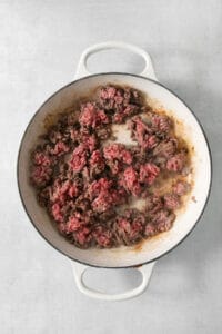 Cowboy casserole with ground beef in a skillet on a white background.