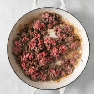 Cowboy casserole with ground beef in a skillet on a white background.