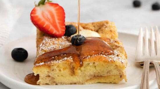 A slice of french toast is being drizzled with syrup.