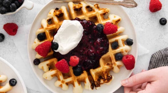 Waffles with berries and whipped cream on a plate.
