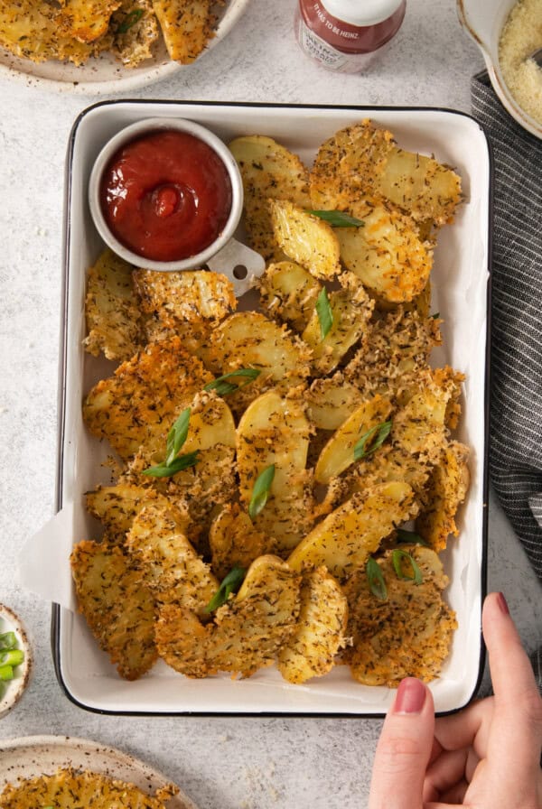 A tray of potato chips with ketchup and dipping sauce.