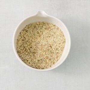 Buckwheat groats in a white bowl on a grey background.