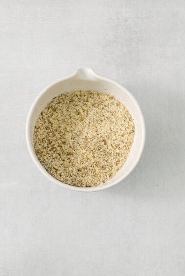 Buckwheat groats in a white bowl on a grey background.