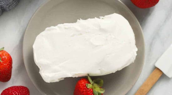 A piece of whipped cream with strawberries on a plate.
