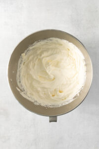Whipped cream in a metal bowl on a white background.