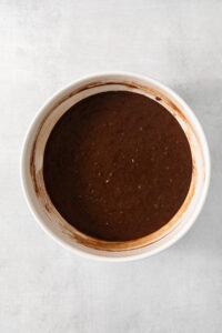 A bowl of chocolate batter on a white surface.