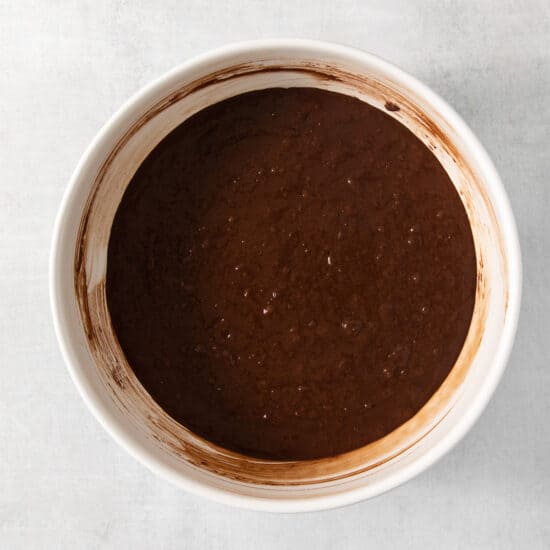 A bowl of chocolate batter on a white surface.
