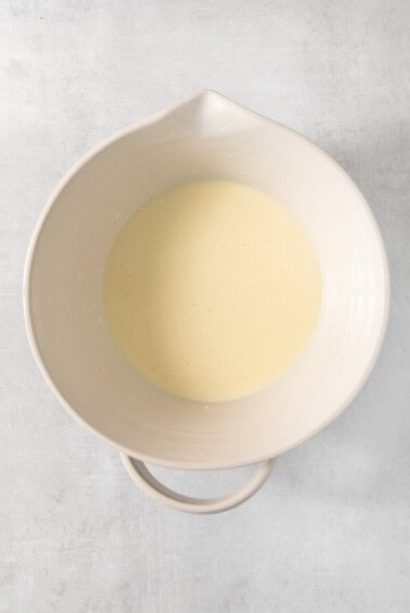 A white bowl filled with liquid on a grey background.