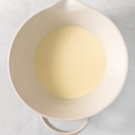 A white bowl filled with liquid on a grey background.