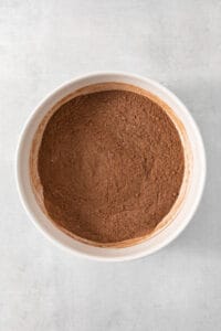 Cocoa powder in a white bowl on a white background.