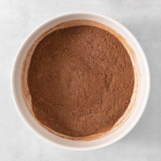 Cocoa powder in a white bowl on a white background.