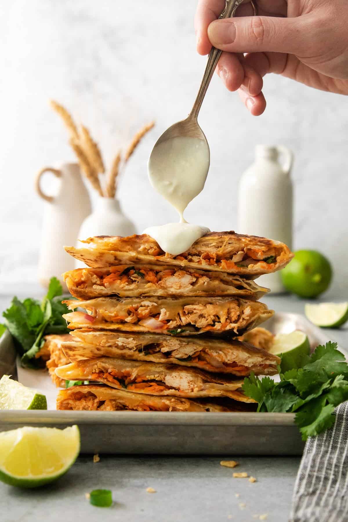 A stack of chicken quesadillas on a plate with a scoop of guacamole.