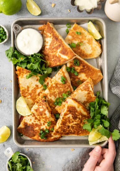 Quesadillas on a tray with limes and cilantro.
