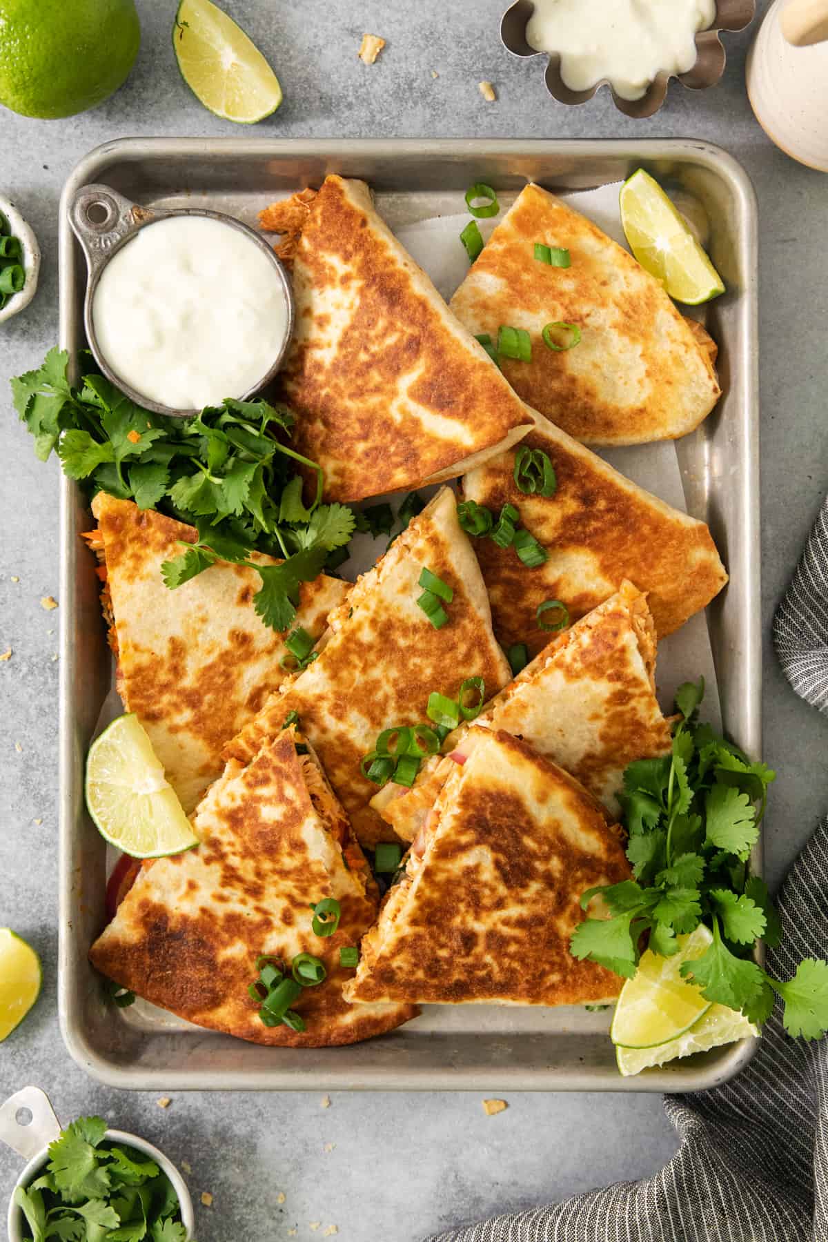 Chicken quesadillas on a tray with lime wedges.