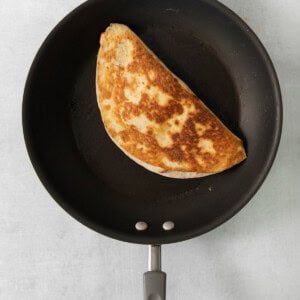 A quesadilla is being cooked in a frying pan.