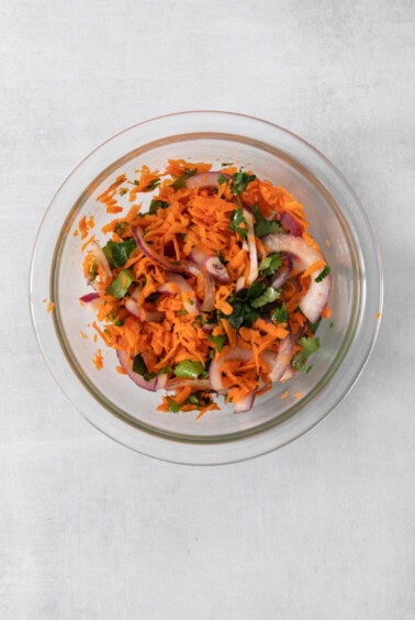 Carrot and onion salad in a glass bowl.