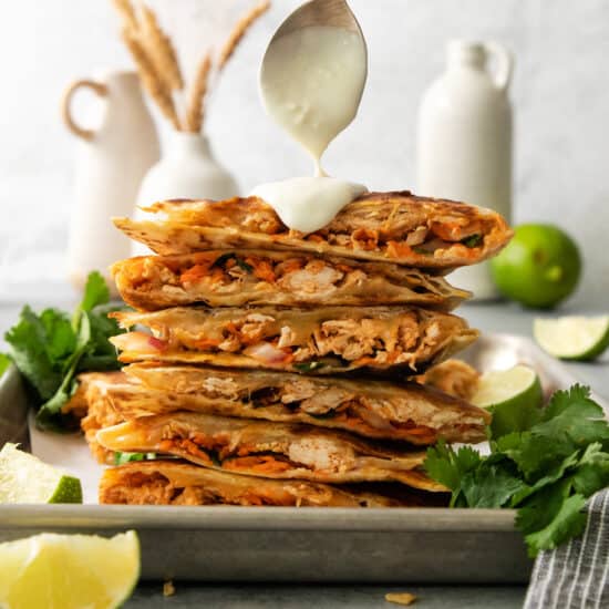 A stack of quesadillas with a drizzle of sauce.