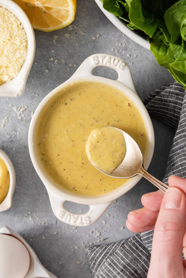 A person is pouring a sauce into a bowl.