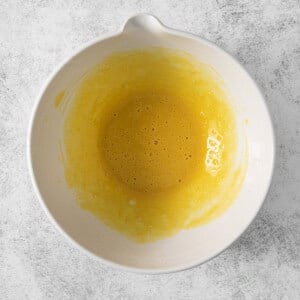 A white bowl with yellow liquid in it.