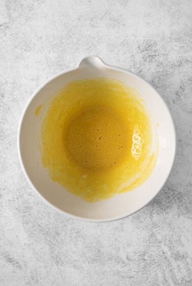 A white bowl with yellow liquid in it.
