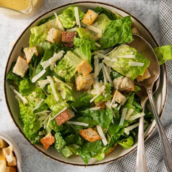 A bowl of caesar salad with croutons and dressing.