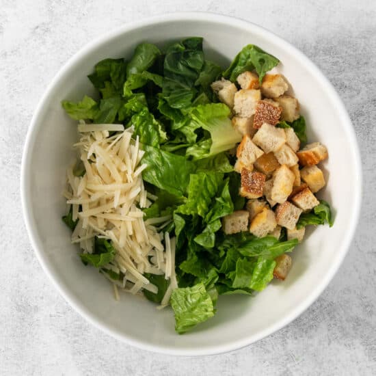 Caesar salad with croutons and croutons in a white bowl.