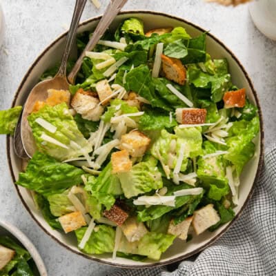 A bowl of caesar salad with croutons and parmesan cheese.