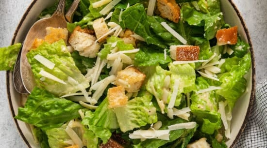 A bowl of caesar salad with croutons and parmesan cheese.