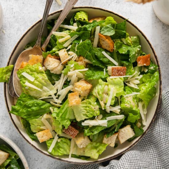 A bowl of caesar salad with croutons and parmesan cheese.