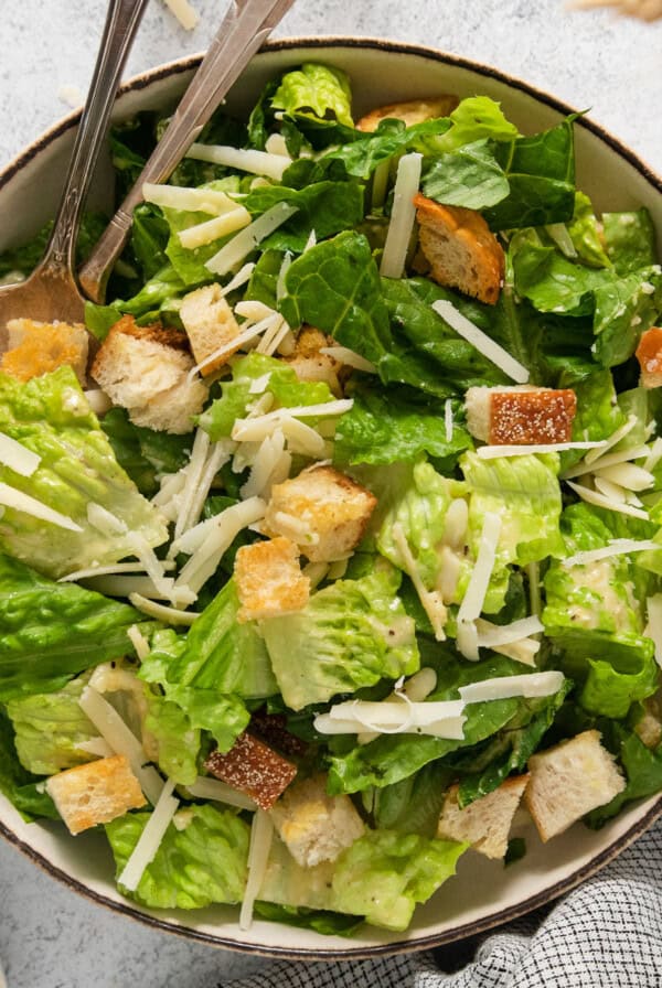 A bowl of caesar salad with croutons and parmesan cheese.