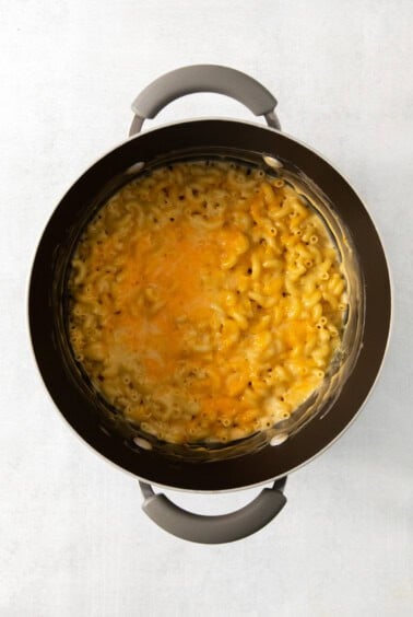 Macaroni and cheese in a pot on a white surface.