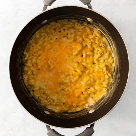 Macaroni and cheese in a pot on a white surface.